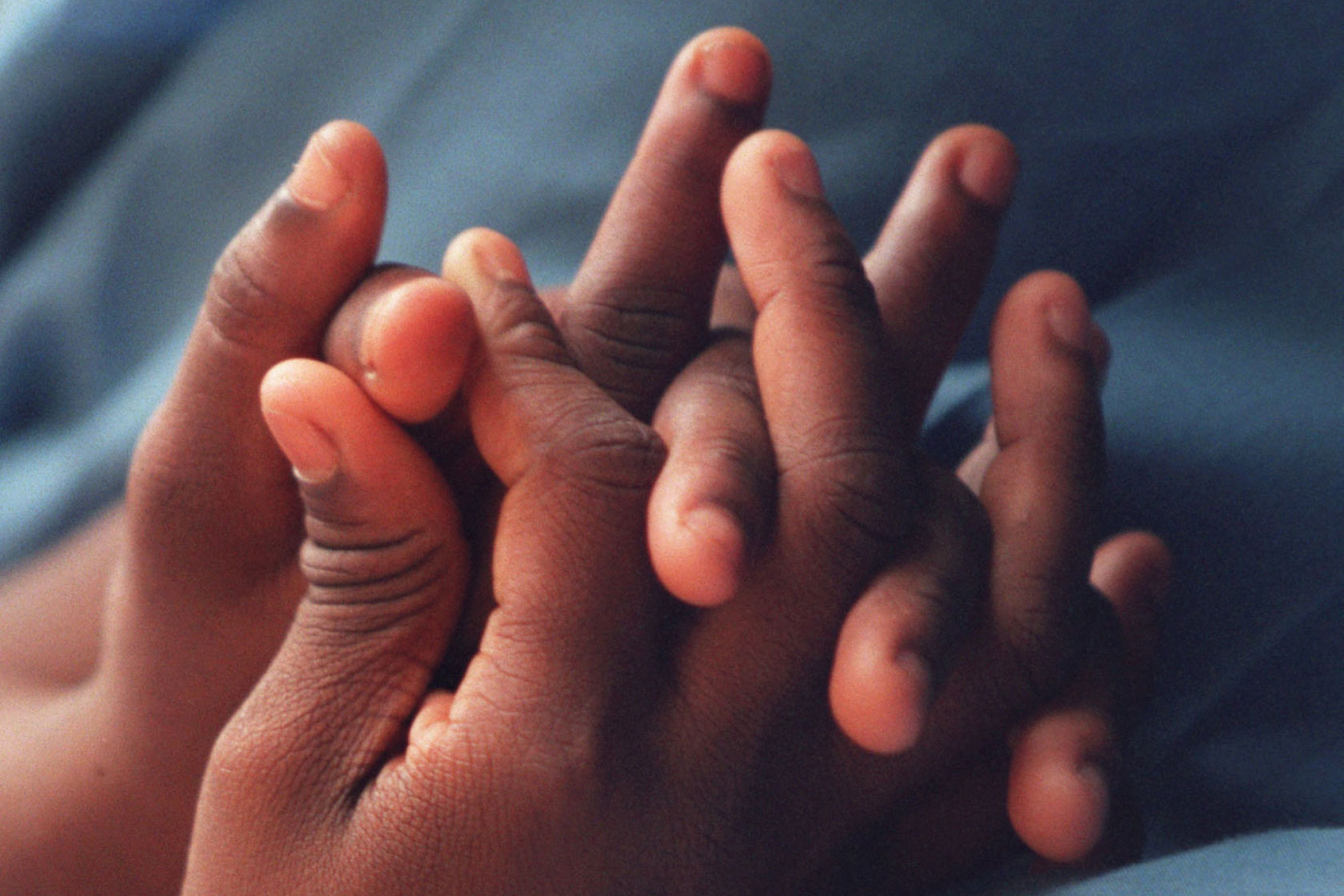 A closeup of the hands of two students at a school for the blind.